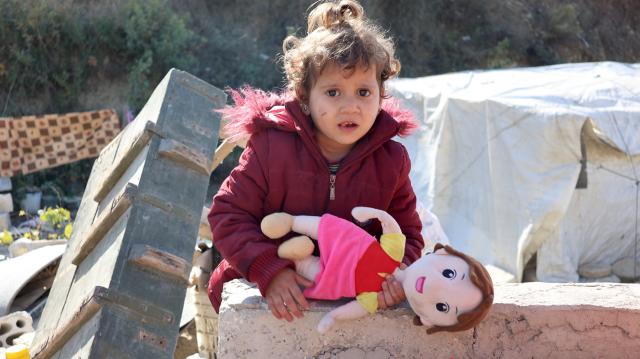(251130) -- KHIRBET AL-JOZ, Nov. 30, 2025 (Xinhua) -- A child holds a doll outside a makeshift tent at a camp in Khirbet al-Joz of northwestern Idlib province, Syria, Nov. 20, 2025.
  TO GO WITH "Feature: Stuck in tents and cut off from aid, displaced Syrians in NW border camp face another hard winter" (Str/Xinhua)