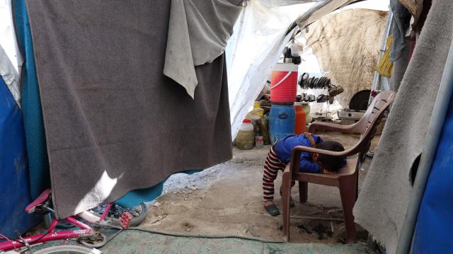 (251130) -- KHIRBET AL-JOZ, Nov. 30, 2025 (Xinhua) -- A child leans over on a chair at a camp in Khirbet al-Joz of northwestern Idlib province, Syria, Nov. 20, 2025.
  TO GO WITH "Feature: Stuck in tents and cut off from aid, displaced Syrians in NW border camp face another hard winter" (Str/Xinhua)