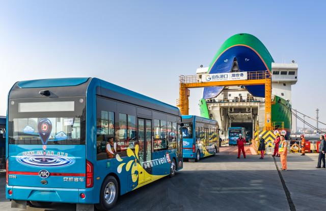 (251130) -- JINAN, Nov. 30, 2025 (Xinhua) -- A drone photo taken on Nov. 30, 2025 shows electric buses lining up to board a new energy vehicle carrier at Yantai Port in east China's Shandong Province. (Photo by Zhang Chao/Xinhua)