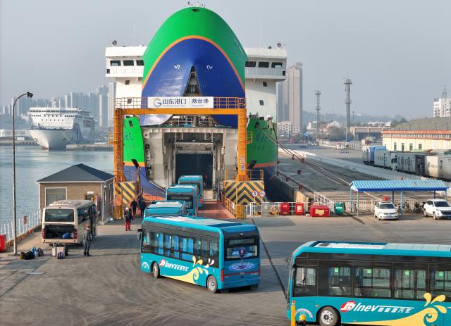 (251130) -- JINAN, Nov. 30, 2025 (Xinhua) -- A drone photo taken on Nov. 30, 2025 shows electric buses lining up to board a new energy vehicle carrier at Yantai Port in east China's Shandong Province. (Photo by Tang Ke/Xinhua)