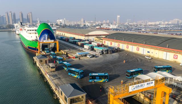 (251130) -- JINAN, Nov. 30, 2025 (Xinhua) -- An aerial drone photo taken on Nov. 30, 2025 shows electric buses lining up to board a new energy vehicle carrier at Yantai Port in east China's Shandong Province. (Photo by Zhang Chao/Xinhua)