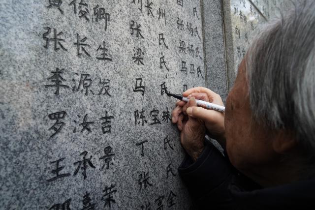 (251201) -- BEIJING, Dec. 1, 2025 (Xinhua) -- Nanjing Massacre survivor Xia Shuqin uses a black pen to renew the names on the "wailing wall" outside the Memorial Hall of the Victims in Nanjing Massacre by Japanese Invaders in Nanjing, east China's Jiangsu Province, Nov. 30, 2025. Families of the victims of the Nanjing Massacre on Sunday gathered at a memorial hall in Nanjing to commemorate their loved ones. (Photo by Liu Zhenrui/Xinhua)