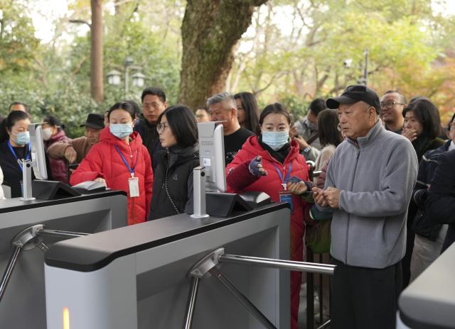 (251201) -- HANGZHOU, Dec. 1, 2025 (Xinhua) -- Tourists enter the Lingyin Feilai Peak Scenic Area in Hangzhou, east China's Zhejiang Province, Dec. 1, 2025. The Lingyin Feilai Peak Scenic Area in Hangzhou officially offers free admission from Monday. The entire scenic area including major cultural sites such as Lingyin Temple, Yongfu Temple and Taoguang Temple, are all for free entry. Visitors need to enter the scenic area with real-name reservation based on time slots. (Xinhua/Weng Xinyang)