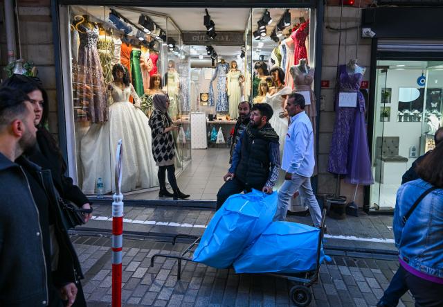 (251201) -- ISTANBUL, Dec. 1, 2025 (Xinhua) -- A porter loads goods in front of a bridal shop near the Grand Bazaar in Istanbul, Türkiye, Nov. 25, 2025. In the old quarters of Istanbul, one often encounters a familiar scene: men weaving through narrow streets, carrying heavy loads on their backs or pushing them on handcarts. Known in Turkish as "hamal," these traditional porters represent a profession that dates back to the Ottoman era and endures to this day.
   The porters'tools are simple -- a thick shoulder strap or a sturdy handcart. Dozens of kilograms, sometimes even loads exceeding a hundred kilograms, are lifted and transported with steady precision before disappearing into the maze-like streets.
   The Grand Bazaar, the Spice Bazaar, and the commercial district of Eminonu are among Istanbul's oldest and busiest trading hubs. Dense shopfronts, heavy foot traffic, and a network of narrow alleys and intersections leave little room for motor vehicles, which have allowed the hamal profession to survive and remain indispensable.
   In these labyrinthine streets, they shoulder countless small-scale logistics tasks, quietly sustaining the commercial lifeblood of the city. In Istanbul, being a porter is not only a traditional craft -- it is a foundational force that has supported the city's commercial vitality for centuries. (Xinhua/Liu Lei)