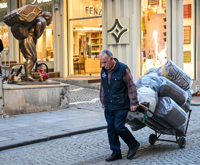 (251201) -- ISTANBUL, Dec. 1, 2025 (Xinhua) -- A porter transports goods with a handcart in the Eminonu commercial district of Istanbul, Türkiye, Nov. 25, 2025. In the old quarters of Istanbul, one often encounters a familiar scene: men weaving through narrow streets, carrying heavy loads on their backs or pushing them on handcarts. Known in Turkish as "hamal," these traditional porters represent a profession that dates back to the Ottoman era and endures to this day.
   The porters'tools are simple -- a thick shoulder strap or a sturdy handcart. Dozens of kilograms, sometimes even loads exceeding a hundred kilograms, are lifted and transported with steady precision before disappearing into the maze-like streets.
   The Grand Bazaar, the Spice Bazaar, and the commercial district of Eminonu are among Istanbul's oldest and busiest trading hubs. Dense shopfronts, heavy foot traffic, and a network of narrow alleys and intersections leave little room for motor vehicles, which have allowed the hamal profession to survive and remain indispensable.
   In these labyrinthine streets, they shoulder countless small-scale logistics tasks, quietly sustaining the commercial lifeblood of the city. In Istanbul, being a porter is not only a traditional craft -- it is a foundational force that has supported the city's commercial vitality for centuries. (Xinhua/Liu Lei)