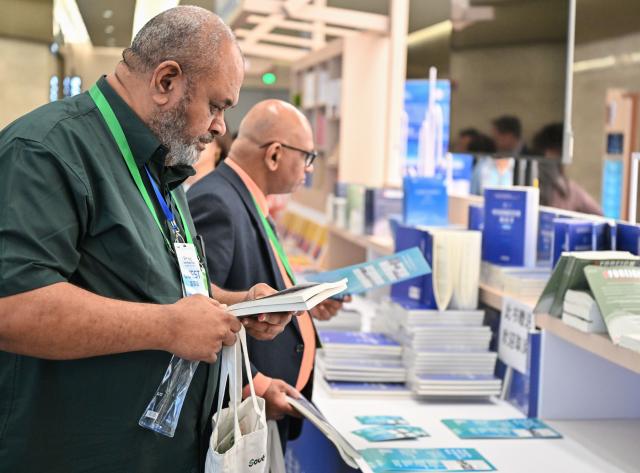 (251201) -- GUANGZHOU, Dec. 1, 2025 (Xinhua) -- Participants browses books during the 2025 Understanding China Conference in Guangzhou, south China's Guangdong Province, Dec. 1, 2025. The 2025 Understanding China Conference, themed "New Plan, New Development, New Choices -- Chinese Modernization and New Vision for Global Governance," is held in Guangzhou, the capital of south China's Guangdong Province. (Xinhua/Xiao Ennan)
