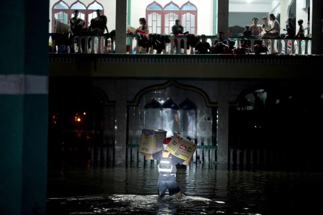 (251202) -- BEIJING, Dec. 2, 2025 (Xinhua) -- A rescuer walks through flood water to bring relief supplies for disaster-affected communities at a temporary shelter in Medan, North Sumatra, Indonesia on Nov. 29, 2025. The death toll from recent floods and landslides across three provinces on Indonesia's Sumatra Island has risen to 502 with 508 missing, the National Disaster Management Agency (BNPB) said on Monday. (Photo by Saddam/Xinhua)