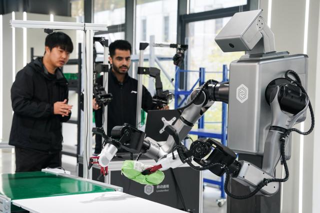 (251202) -- HEFEI, Dec. 2, 2025 (Xinhua) -- Ahmed Medhat Mostafa Elsayed (R) tries operating a parcel sorting robot at the pre-training venue for the Embodied Artificial Intelligence (EAI) robots data collection in Hefei, east China's Anhui Province, Nov. 28, 2025. The 23-year-old Ahmed Medhat Mostafa Elsayed is an Egyptian student who is currently doing research in particle physics at the University of Science and Technology of China in Hefei.
    Elsayed came to China at the age of ten in 2012. Influenced by his father, who works in the physics area, Elsayed gradually developed a strong interest in physics. After graduating from Sichuan University of Science and Engineering with a bachelor's degree in physics two years ago, he entered the University of Science and Technology of China for his postgraduate study. 
    Now Elsayed, whose research topic focuses on heavy neutrinos, plans to apply for the doctoral degree here, hoping he could make some influential scientific research achievements in the future and  could become a bridge on academic exchange between China and the world. (Xinhua/Du Yu)