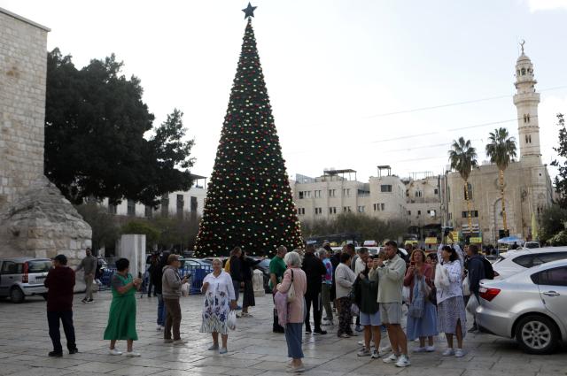 (251202) -- BETHLEHEM, Dec. 2, 2025 (Xinhua) -- Tourists visit the main Christmas tree in Manger Square in Bethlehem in the West Bank, Dec. 1, 2025. With Christmas nearing, Manger Square and the Church of the Nativity are welcoming more international visitors, bringing hope for a strong and festive season. (Photo by Mamoun Wazwaz/Xinhua)