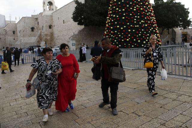 (251202) -- BETHLEHEM, Dec. 2, 2025 (Xinhua) -- Tourists walk around the main Christmas tree in Manger Square in Bethlehem in the West Bank, Dec. 1, 2025. With Christmas nearing, Manger Square and the Church of the Nativity are welcoming more international visitors, bringing hope for a strong and festive season. (Photo by Mamoun Wazwaz/Xinhua)