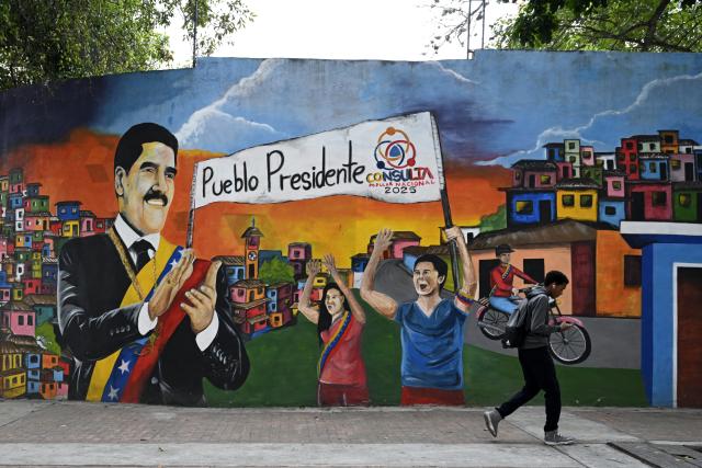 (251202) -- CARACAS, Dec. 2, 2025 (Xinhua) -- A man walk by a wall painting supporting Venezuelan President Nicolas Maduro in Caracas, Venezuela, Dec. 2, 2025. (Xinhua/Li Muzi)