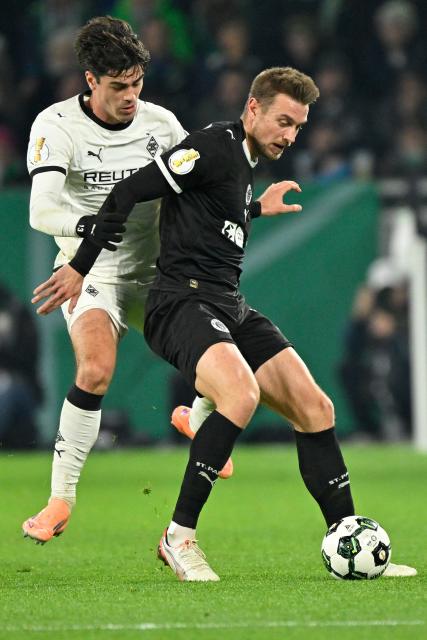 (251203) -- MOENCHENGLADBACH, Dec. 3, 2025 (Xinhua) -- Giovanni Reyna (rear) of Borussia Moenchengladbach vies with Hauke Finn Wahl of FC St. Pauli during the German Cup football round of 16 match between Borussia Moenchengladbach and FC St. Pauli in Moenchengladbach, Germany, Dec. 2, 2025. (Photo by Ulrich Hufnagel/Xinhua)