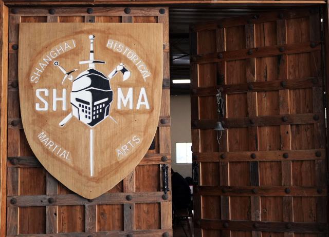 (251203) -- SHANGHAI, Dec. 3, 2025 (Xinhua) -- This photo shows the gate of the Shanghai Historical Martial Arts (SHMA) club in Shanghai, east China, Nov. 22, 2025. Ismet Himmet, with his Chinese name You Lihan, speaks fluent Chinese and has devoted more than thirty years to Chinese martial arts. Himmet, now 48, began learning kung fu in 1991. Nine years later, he traveled to China for the first time. From 2006 he started teaching Chinese martial arts full-time in Germany. At XUAN-Gong Fu Academy, a kung fu school that Himmet established in Berlin, students of all ages practise Tai Chi, Ba Gua Zhang, Xingyiquan and other kung fu styles every day. In his view, martial arts are not just a sport, but also a way of living and something that helps the mind turn toward the positive.
  Thousands of kilometers away, in east China's Shanghai, She Yuran, known as "A Xiao", is engaged in a similar career as Himmet. Born in Sichuan of China, She Yuran studied Historical European Martial Arts (HEMA) at college. His interest in HEMA grew into a deep study of historical weapons and combat methods.
  In 2015, She Yuran co-founded the Shanghai Historical Martial Arts (SHMA) club, offering systematic training in both European and Chinese martial arts. SHMA now has more than 200 members, over half of whom study German swordsmanship. 
  While Ismet Himmet helps Germans understand the philosophy and practice of Chinese martial arts, She Yuran brings European sword traditions to young Chinese practitioners. Their commitment shows how martial arts can carry culture across borders, allowing mutual understanding to grow through their fists and blades. (Xinhua/Liu Ying)