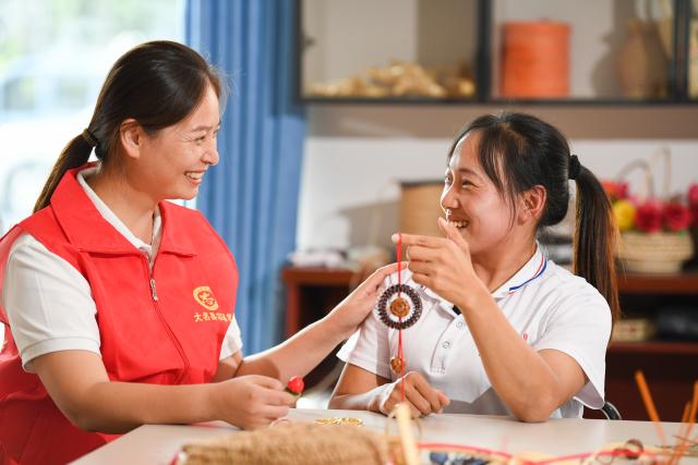 (251203) -- SHIJIAZHUANG, Dec. 3, 2025 (Xinhua) -- This photo taken on Sept. 20, 2025 shows Gu Sui (L), founder of Yushan Center, a local institution providing free straw plaiting training for people with disabilities, chatting with Li Peipei, a craftswoman working at the center, in Daming County, Handan City, north China's Hebei Province. TO GO WITH "Across China: Millennia-old craft weaves hope, opportunity for people with disabilities in north China" (Photo by Dong Yuan/Xinhua)