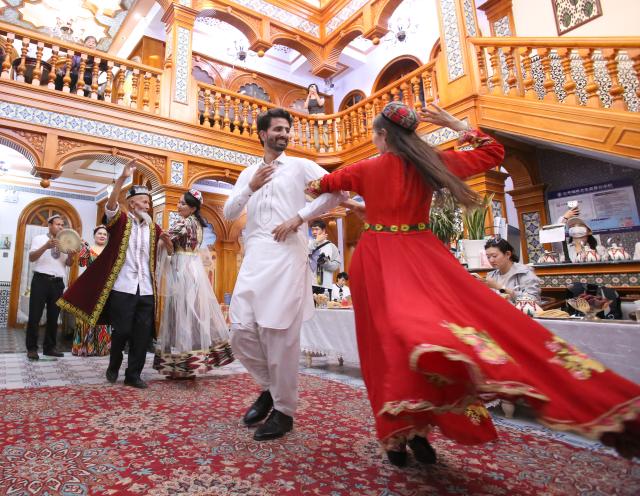 (251203) -- URUMQI, Dec. 3, 2025 (Xinhua) -- A Pakistani tourist (2nd R, front) dances with a staff member at a homestay, in the Kashgar Ancient City scenic spot, northwest China's Xinjiang Uygur Autonomous Region, Sept. 10, 2025. (Xinhua/Cheng Li)