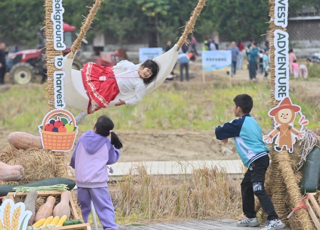 (251203) -- LIUZHOU, Dec. 3, 2025 (Xinhua) -- Children play with a swing in the field at Silang village in Liujiang District, Liuzhou City, south China's Guangxi Zhuang Autonomous Region, Nov. 1, 2025. In recent years, Liujiang District of Liuzhou City has leveraged its thriving rural industries and vibrant agricultural economy to expand its tourism business. In the first three quarters of this year, Liujiang District received a total of 5.9975 million visits, a year-on-year increase of 11.16 percent, with tourism-related revenue of 6.006 billion yuan (850.26 million U.S. dollars), up 9.91 percent compared to the same period last year. (Xinhua/Huang Xiaobang)