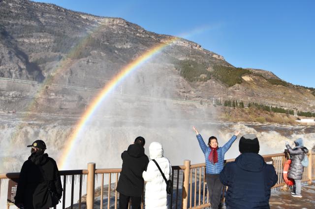 (251203) -- JIXIAN, Dec. 3, 2025 (Xinhua) -- Tourists take photos with a double rainbow over the Hukou Waterfall in the background in Jixian County, north China's Shanxi Province, Dec. 3, 2025. (Photo by Lyu Guiming/Xinhua)