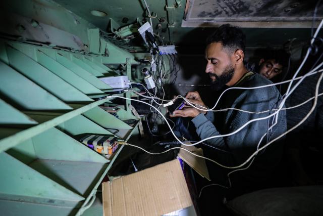 (251203) -- GAZA, Dec. 3, 2025 (Xinhua) -- Palestinian men use power source inside the abandoned Israeli army vehicle, in Gaza City, on Nov. 30, 2025. TO GO WITH "Feature: From army vehicle to power source -- a Gazan's retooling of war" (Photo by Rizek Abdeljawad/Xinhua)