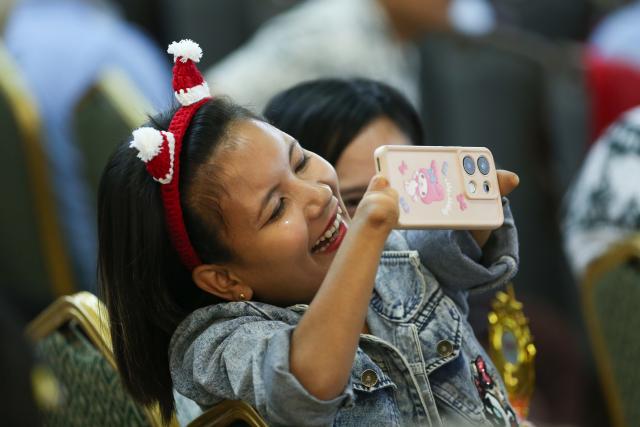 (251204) -- BEIJING, Dec. 4, 2025 (Xinhua) -- A young woman takes photos during a ceremony to mark the International Day of Persons with Disabilities in Yangon, Myanmar, Dec. 2, 2025. (Xinhua/Myo Kyaw Soe)