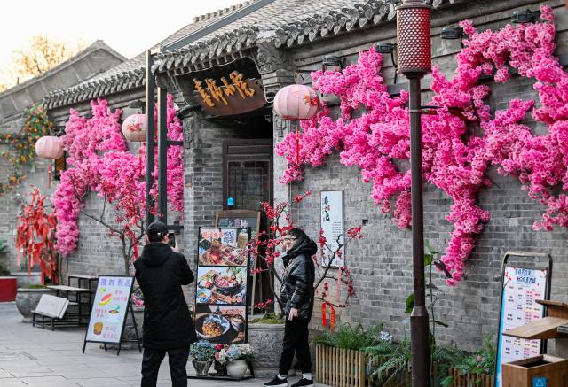 (251204) -- TIANJIN, Dec. 4, 2025 (Xinhua) -- Tourists take pictures at Yangliuqing ancient town in Tianjin, north China, on Dec. 3, 2025. Sitting on the outskirts of the port city of Tianjin, Yangliuqing ancient town is a tourist town that is well-known for its woodblock new year pictures. It is run through by the Grand Canal, the world's longest man-made waterway. (Xinhua/Zhao Zishuo)