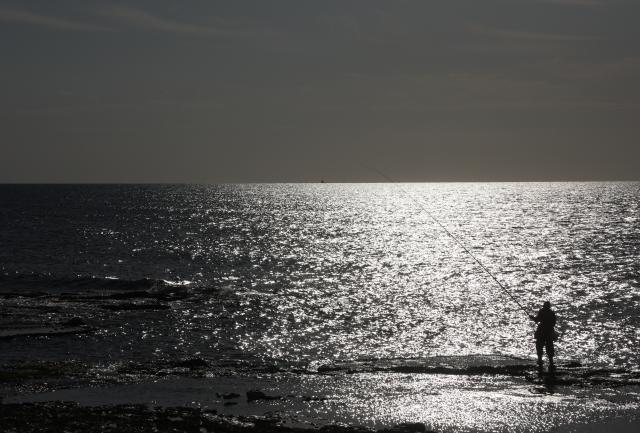 (251204) -- HAIFA, Dec. 4, 2025 (Xinhua) -- A man fishes on the beach in Haifa, northern Israel, Dec. 3, 2025. (Photo by Gil Cohen Magen/Xinhua)