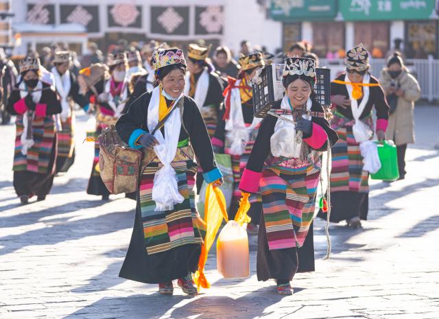 (251204) -- LHASA, Dec. 4, 2025 (Xinhua) -- Women in festive attire walk on Barkhor Street in Lhasa, southwest China's Xizang Autonomous Region, Dec. 4, 2025. Xizang marked the annual Fairy's Day, also known as the "Women's Festival", on Thursday, the 15th day of the tenth month in the Tibetan calendar. Women in festive attire were seen on the streets carrying hada scarves and barley wine as they headed to Jokhang Temple to pay homage to Palden Lhamo, a goddess in Tibetan Buddhism. (Xinhua/Tenzin Nyida)