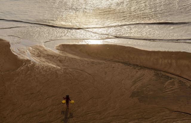 (251204) -- XIAPU, Dec. 4, 2025 (Xinhua) -- A person in fisherman outfit walks on the tidal flats in Dongbi Village in Sansha Town, Xiapu County, southeast China's Fujian Province, Dec. 3, 2025. Sansha Town in Xiapu County, blessed with unique natural resources and rich historical culture, has been walking a distinctive path to rural revitalization by orchestrating tourist attractions such as high-end homestays, tidal flat landscape and local specialty food with rural development. (Xinhua/Wei Peiquan)