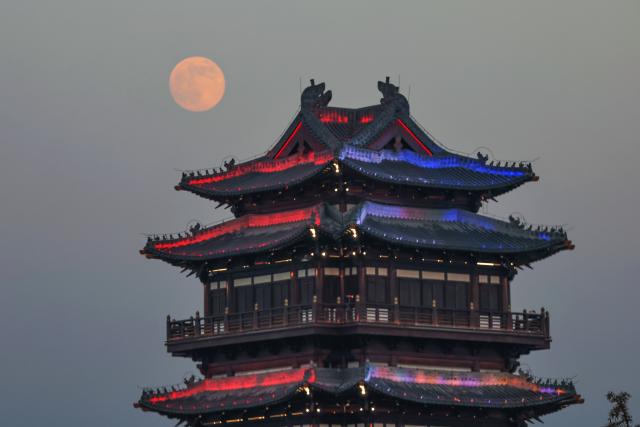 (251204) -- BEIJING, Dec. 4, 2025 (Xinhua) -- A full moon is pictured over a tower in Lianyungang City, east China's Jiangsu Province, Dec. 4, 2025. This year's second-largest full moon to the eyes of lunar observers will appear on Friday morning, but the best viewing time falls on Thursday evening. (Photo by Wang Jianmin/Xinhua)