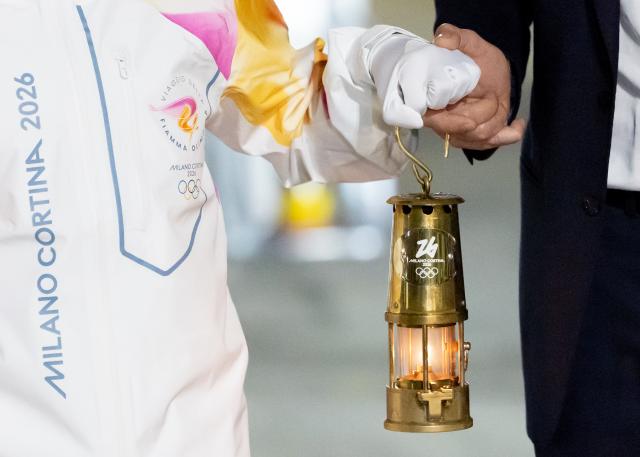 (251205) -- ROME, Dec. 5, 2025 (Xinhua) -- Italy's tennis player and Olympic champion Jasmine Paolini (L) and Giovanni Malago, president of the Milan-Cortina organizing committee, walk down the gangway with a lantern holding the flame of 2026 Milan-Cortina Olympic Winter Games at Fiumicino Airport in Rome, Italy, Dec. 4, 2025. The Olympic flame for the 2026 Winter Games arrived in Rome, Italy on Thursday afternoon, marking the start of a series of torch relay events. (Xinhua/Li Jing)