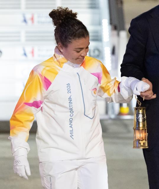 (251205) -- ROME, Dec. 5, 2025 (Xinhua) -- Italy's tennis player and Olympic champion Jasmine Paolini (L) and Giovanni Malago, president of the Milan-Cortina organizing committee, walk down the gangway with a lantern holding the flame of 2026 Milan-Cortina Olympic Winter Games at Fiumicino Airport in Rome, Italy, Dec. 4, 2025. The Olympic flame for the 2026 Winter Games arrived in Rome, Italy on Thursday afternoon, marking the start of a series of torch relay events. (Xinhua/Li Jing)