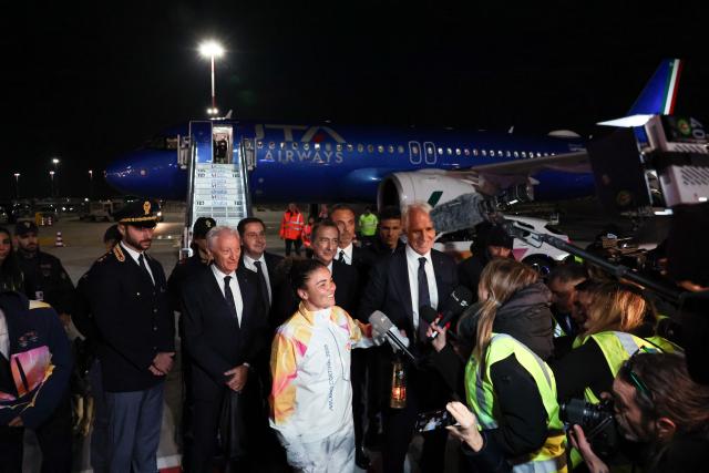 (251205) -- ROME, Dec. 5, 2025 (Xinhua) -- Italy's tennis player and Olympic champion Jasmine Paolini and Giovanni Malago, president of the Milan-Cortina organizing committee, talk with the press with a lantern holding the flame of 2026 Milan-Cortina Olympic Winter Games at Fiumicino Airport in Rome, Italy, Dec. 4, 2025. The Olympic flame for the 2026 Winter Games arrived in Rome, Italy on Thursday afternoon, marking the start of a series of torch relay events. (Xinhua/Li Jing)