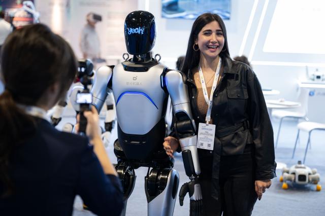 (251205) -- MACAO, Dec. 5, 2025 (Xinhua) -- A visitor poses for pictures with a humanoid robot at the 2025 Global Artificial Intelligence Machines and Electronics Expo (AIE) in Macao, south China, Dec. 4, 2025. The 2025 AIE kicked off in China's Macao Special Administrative Region (SAR) on Thursday, focusing on cooperation among the Guangdong-Hong Kong-Macao Greater Bay Area and global opportunities.
   The exhibition, held simultaneously in Macao and Zhuhai, south China's Guangdong Province, features over 1,000 companies from both the domestic and overseas markets, drawing buyers from more than 30 countries and regions, according to the organizer. (Xinhua)