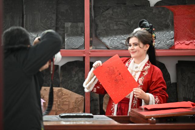 (251205) -- BEIJING, Dec. 5, 2025 (Xinhua) -- A tourist takes photos after making a woodblock new year picture at Yangliuqing ancient town in Tianjin, north China, on Dec. 3, 2025.
  Sitting on the outskirts of the port city of Tianjin, Yangliuqing ancient town is a tourist town that is well-known for its woodblock new year pictures. (Xinhua/Zhao Zishuo)