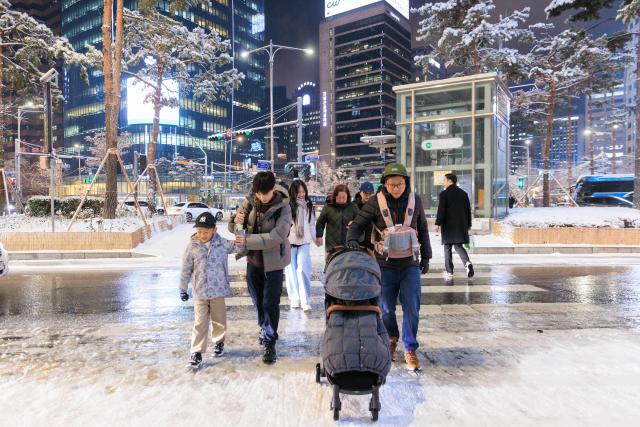 (251205) -- SEOUL, Dec. 5, 2025 (Xinhua) -- People walk in snow in Seoul, South Korea, on Dec. 4, 2025. Seoul on Thursday saw its first snowfall of this year. (Photo by Park Jintaek/Xinhua)