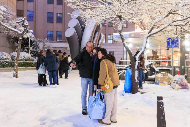 (251205) -- SEOUL, Dec. 5, 2025 (Xinhua) -- People take selfies in Seoul, South Korea, on Dec. 4, 2025. Seoul on Thursday saw its first snowfall of this year. (Photo by Park Jintaek/Xinhua)
