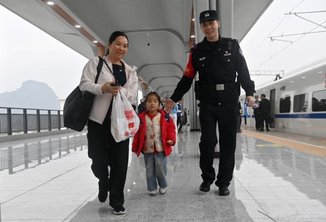 (251205) -- NANNING, Dec. 5, 2025 (Xinhua) -- A staff member guides the passengers to board a train at Pingxiang East Railway Station, in Pingxiang City, south China's Guangxi Zhuang Autonomous Region, on Dec. 5, 2025. The Chongzuo-Pingxiang section of the Nanning-Pingxiang Railway began operation on Friday, marking the full operation of the high-speed railway, which connects the region's capital city Nanning to the border city Pingxiang. (Xinhua/Lu Boan)