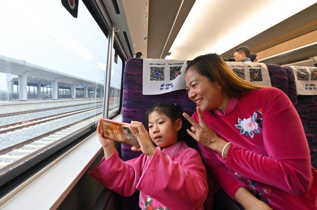 (251205) -- NANNING, Dec. 5, 2025 (Xinhua) -- Tourists take selfies on a bullet train running from Pingxiang to Nanning in south China's Guangxi Zhuang Autonomous Region, on Dec. 5, 2025. The Chongzuo-Pingxiang section of the Nanning-Pingxiang Railway began operation on Friday, marking the full operation of the high-speed railway, which connects the region's capital city Nanning to the border city Pingxiang. (Xinhua/Lu Boan)