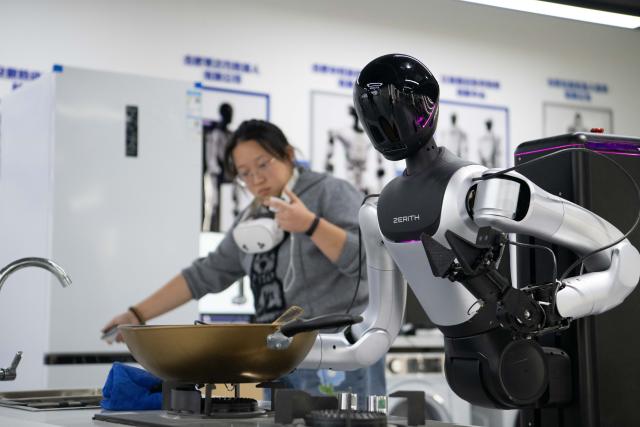 (251205) -- HEFEI, Dec. 5, 2025 (Xinhua) -- A technician teaches a humanoid robot to wipe the kitchen stove at a data collection pre-training center for humanoid robots in Hefei, east China's Anhui Province, Dec. 4, 2025. Using technologies such as physical simulation, virtual reality, and big data modelling, the data collection pre-training center helps robots adapt to diverse tasks from handling precision components to daily household services, while shortening research and development cycles and reducing relevant costs.
  The center has attracted companies to test their robots here through structured courses and assessments. (Xinhua/Zhang Duan)