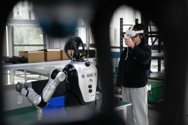 (251205) -- HEFEI, Dec. 5, 2025 (Xinhua) -- A technician teaches a humanoid robot to pick and sort components at a data collection pre-training center for humanoid robots in Hefei, east China's Anhui Province, Dec. 4, 2025. Using technologies such as physical simulation, virtual reality, and big data modelling, the data collection pre-training center helps robots adapt to diverse tasks from handling precision components to daily household services, while shortening research and development cycles and reducing relevant costs.
  The center has attracted companies to test their robots here through structured courses and assessments. (Xinhua/Zhang Duan)