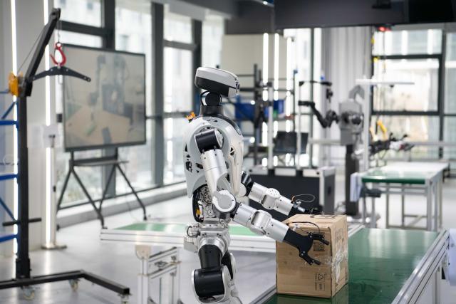 (251205) -- HEFEI, Dec. 5, 2025 (Xinhua) -- A humanoid robot conducts box-carrying training at a data collection pre-training center for humanoid robots in Hefei, east China's Anhui Province, Dec. 4, 2025. Using technologies such as physical simulation, virtual reality, and big data modelling, the data collection pre-training center helps robots adapt to diverse tasks from handling precision components to daily household services, while shortening research and development cycles and reducing relevant costs.
  The center has attracted companies to test their robots here through structured courses and assessments. (Xinhua/Zhang Duan)