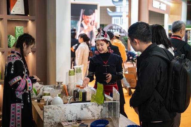 (251205) -- PU'ER, Dec. 5, 2025 (Xinhua) -- An exhibitor (C) introduces coffee products to customers at the 2025 China (Pu'er) International Coffee Expo and Pu'er Tea Expo & Trade Fair in Pu'er, southwest China's Yunnan Province, Dec. 5, 2025. The three-day dual-expo event kicked off here on Friday, attracting over 100 enterprises from home and abroad. (Xinhua/Wang Guansen)