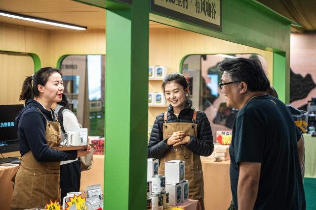 (251205) -- PU'ER, Dec. 5, 2025 (Xinhua) -- An exhibitor (L) introduces coffee products to a customer at the 2025 China (Pu'er) International Coffee Expo and Pu'er Tea Expo & Trade Fair in Pu'er, southwest China's Yunnan Province, Dec. 5, 2025. The three-day dual-expo event kicked off here on Friday, attracting over 100 enterprises from home and abroad. (Xinhua/Wang Guansen)