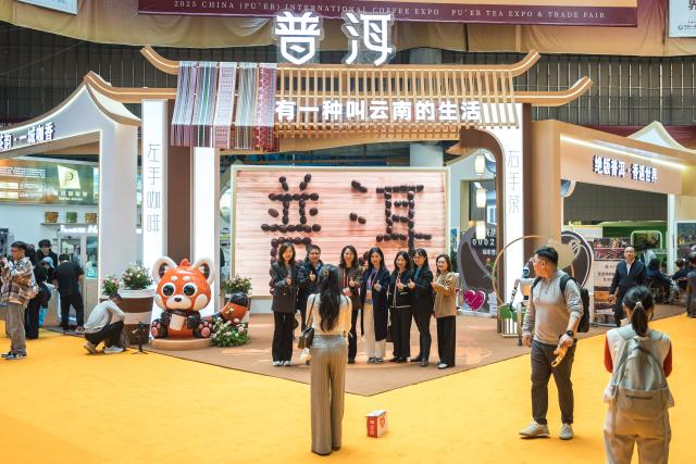 (251205) -- PU'ER, Dec. 5, 2025 (Xinhua) -- Visitors pose for a group photo at the 2025 China (Pu'er) International Coffee Expo and Pu'er Tea Expo & Trade Fair in Pu'er, southwest China's Yunnan Province, Dec. 5, 2025. The three-day dual-expo event kicked off here on Friday, attracting over 100 enterprises from home and abroad. (Xinhua/Wang Guansen)