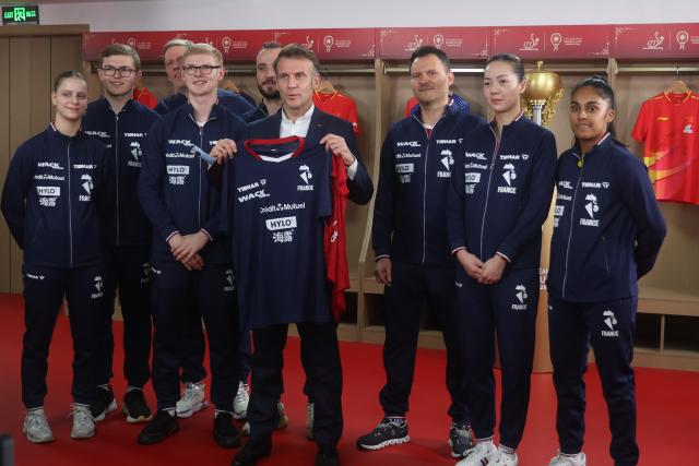 (251205) -- CHENGDU, Dec. 5, 2025 (Xinhua) -- French President Emmanuel Macron receives a jersey from the French team during a meeting with Chinese and French table tennis players participating the ITTF Mixed Team World Cup 2025 in Chengdu, southwest China's Sichuan Province, Dec. 5, 2025. (Photo by Liu Yuchen/Xinhua)