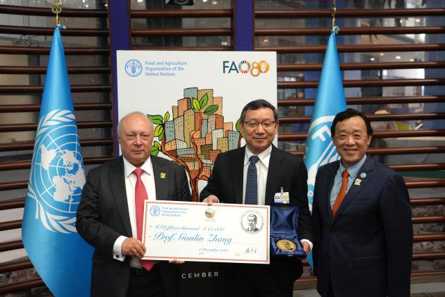 (251205) -- ROME, Dec. 5, 2025 (Xinhua) -- FAO Director-General Qu Dongyu (R) take photos with Zhang Ganlin (C) during the World Soil Day celebration at the FAO headquarters in Rome, Italy, Dec. 5, 2025. Zhang Ganlin, a researcher at the Institute of Soil Science under the Chinese Academy of Sciences, received the 2025 Glinka World Soil Prize on Friday at the World Soil Day celebration held at the headquarters of the Food and Agriculture Organization of the United Nations (FAO) in Rome. (Xinhua/Ren Yaoting)