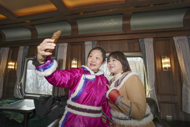 (251206) -- HARBIN, Dec. 6, 2025 (Xinhua) -- Passengers pose for a photo in a carriage of a tourist train dubbed Yichun, in northeast China's Heilongjiang Province, Dec. 6, 2025. A tourist train dubbed Yichun began trial operation on Saturday. More than 40 invited passengers boarded the train at Harbin Railway Station for a trip bound to Yabuli Ski Resort. The train features five themed carriages and offers live band and traditional folk performances for passengers. (Xinhua/Wang Song)