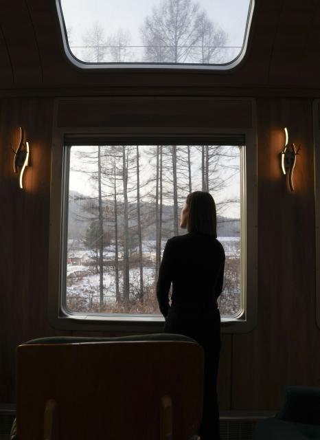 (251206) -- HARBIN, Dec. 6, 2025 (Xinhua) -- A passenger enjoys the winter view in a carriage of a tourist train dubbed Yichun, in northeast China's Heilongjiang Province, Dec. 6, 2025. A tourist train dubbed Yichun began trial operation on Saturday. More than 40 invited passengers boarded the train at Harbin Railway Station for a trip bound to Yabuli Ski Resort. The train features five themed carriages and offers live band and traditional folk performances for passengers. (Xinhua/Wang Song)
