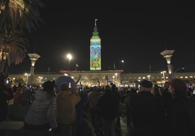 (251206) -- SAN FRANCISCO, Dec. 6, 2025 (Xinhua) -- People watch a light projection on the wall of a building in San Francisco, the United States, Dec. 5, 2025. "Let's Glow SF", a holiday projection arts event, started here on Friday night. Large-scale art projection works will be displayed on the facades of eight iconic buildings in downtown San Francisco from the night of Dec. 5 to 14. (Photo by Liu Yilin/Xinhua)