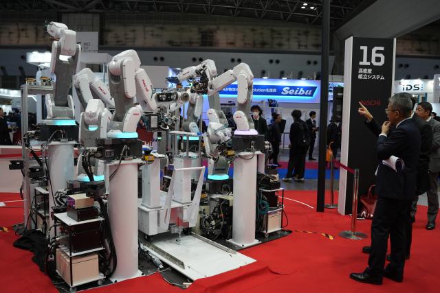 (251206) -- TOKYO, Dec. 6, 2025 (Xinhua) -- People learn about new industrial robots at the exhibition area of Nachi during the 2025 International Robot Exhibition (iREX) in Tokyo, Japan, Dec. 5, 2025. The four-day iREX 2025 concluded here on Saturday, drawing over 670 exhibitors from Japan, China, South Korea, the United States, Germany and other countries and regions. New industrial robots, service robots, catering robots and companion robots integrating AI technology garnered wide attention. (Xinhua/Qian Zheng)