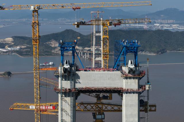 (251206) -- ZHOUSHAN, Dec. 6, 2025 (Xinhua) -- A drone photo shows the construction site of the Shuangyumen super major bridge in east China's Zhejiang Province, Dec. 6, 2025. The pilot cable installation for the Shuangyumen super major bridge, part of the second phase of the Liuheng Highway Bridge project at Ningbo-Zhoushan Port in Zhejiang Province, completed successfully on Saturday. This marks the official commencement of the catway construction on the bridge.
   The project consists of two sea-crossing bridges - Shuangyumen super major bridge and Qinglongmen super major bridge, as well as connection lines between them. Upon completion, the project will further improve the integrated land-sea transportation network of Ningbo-Zhoushan Port. (Xinhua/Huang Zongzhi)